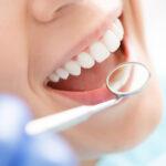 Lächelnde hübsche Frau lässt ihre Zähne vom Zahnarzt in der Praxis untersuchen.