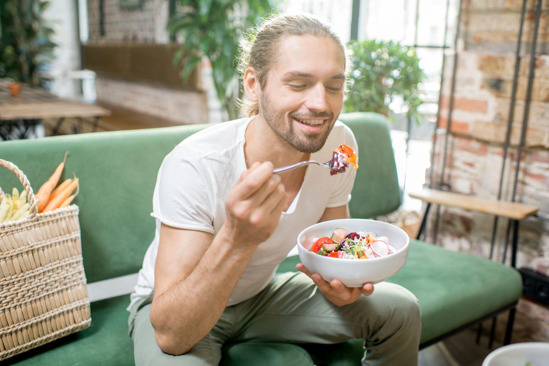 Mann isst frischen Gemüsesalat mit Genuss, Gemüseschneider elektrisch