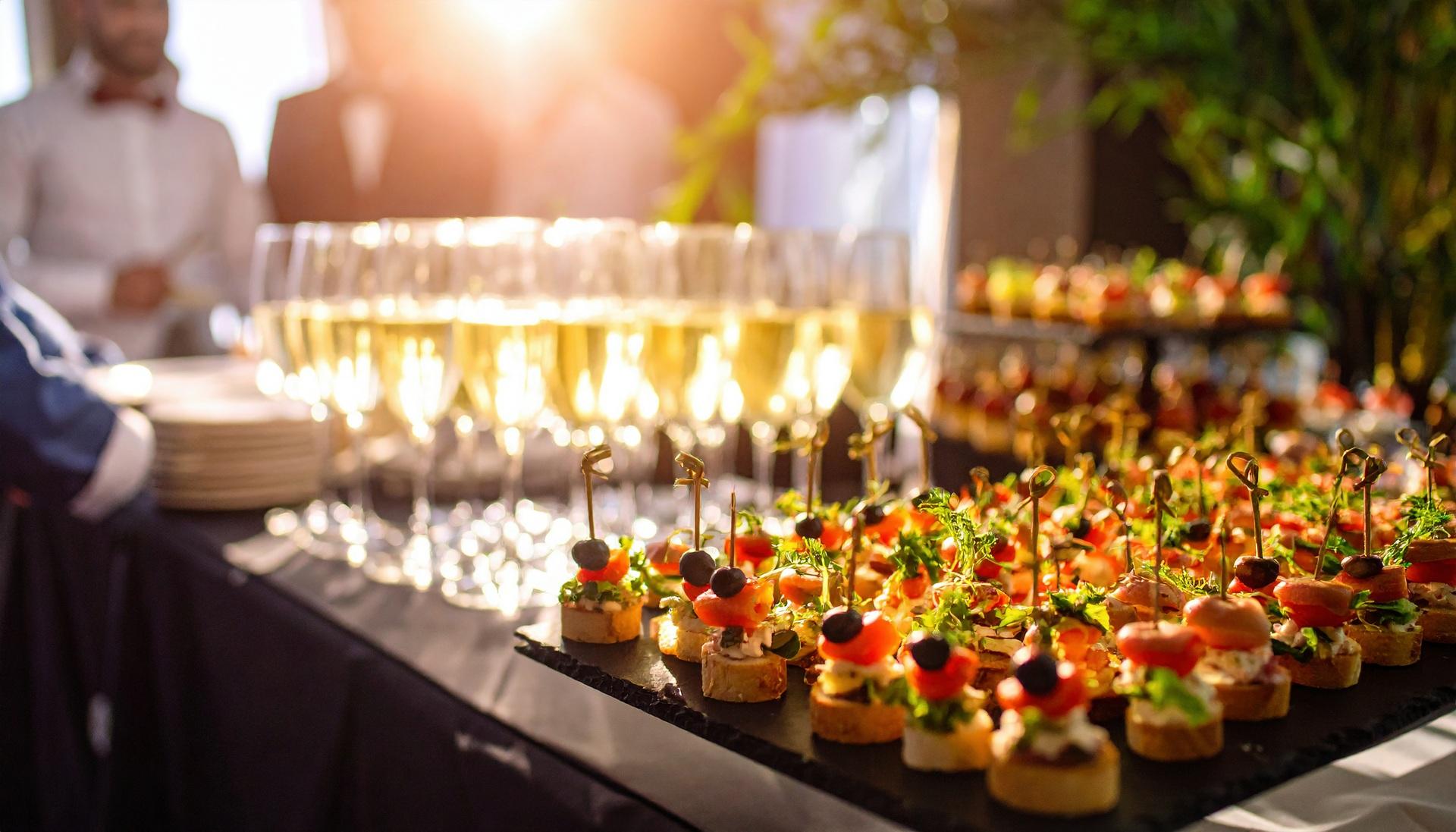 Buffet mit Canapés und gefüllten Sektgläsern bei Sonnenschein | Stehtischhussen